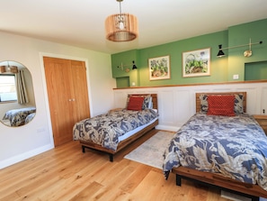 Ein Schlafzimmer mit zwei Betten, einem Holzschrank, einem Spiegel und Wandbildern.