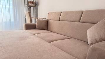 Un sofá seccional color beige en una sala de estar moderna, con un estante metálico contra la pared.