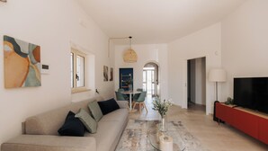 Un salon moderne comprenant un canapé, une table basse, un téléviseur et un coin repas avec des chaises et une table.