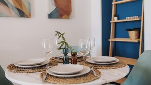 Une table à manger dressée avec des assiettes, des verres et une petite plante servant de centre de table.
