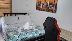 Une chambre à coucher avec un lit, un bureau et un tableau représentant un paysage urbain accroché au mur.