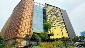 Un bâtiment moderne doté d’une façade originale en forme de nid d’abeilles, d’une entrée en verre et d’un escalier menant à l’entrée.
