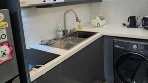 Une cuisine compacte équipée d’un four encastré, d’un évier et d’un lave-linge.
