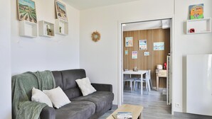 A living room with a grey sofa, a coffee table, and a dining area with a white table and chairs. - Appartement avec terrasse ensoleillée sur le port Olona (Les Sables-d'Olonne)