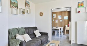 A living room with a sofa, a coffee table, and a dining area with a table and chairs. - Appartement avec terrasse ensoleillée sur le port Olona (Les Sables-d'Olonne)