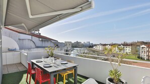 A rooftop terrace with a table set for dining, chairs, a small kitchen area, and potted plants. - Appartement avec terrasse ensoleillée sur le port Olona (Les Sables-d'Olonne)