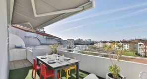 A rooftop terrace with a dining table, chairs, and a potted plant. - Appartement avec terrasse ensoleillée sur le port Olona (Les Sables-d'Olonne)