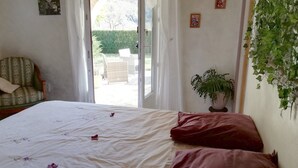 A bedroom with a bed, a chair, a potted plant, and a view through an open door. - Guest Room “La Grande Calade” with Mountain View, Terrace and Wi-Fi (Garde-Colombe)