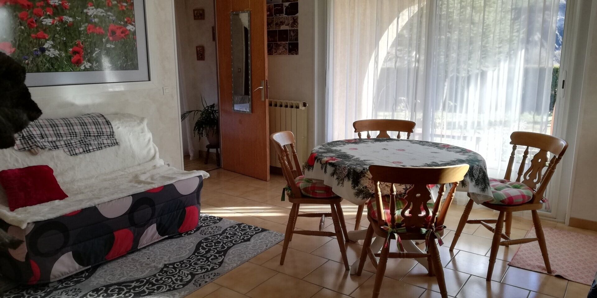 Een woonkamer met een bank, een eettafel met stoelen, een radiator en een raam met gordijnen.