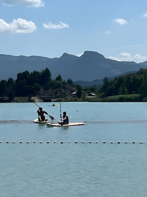 Un lac paisible où l’on peut faire du paddle, un ciel dégagé et des montagnes en arrière-plan.