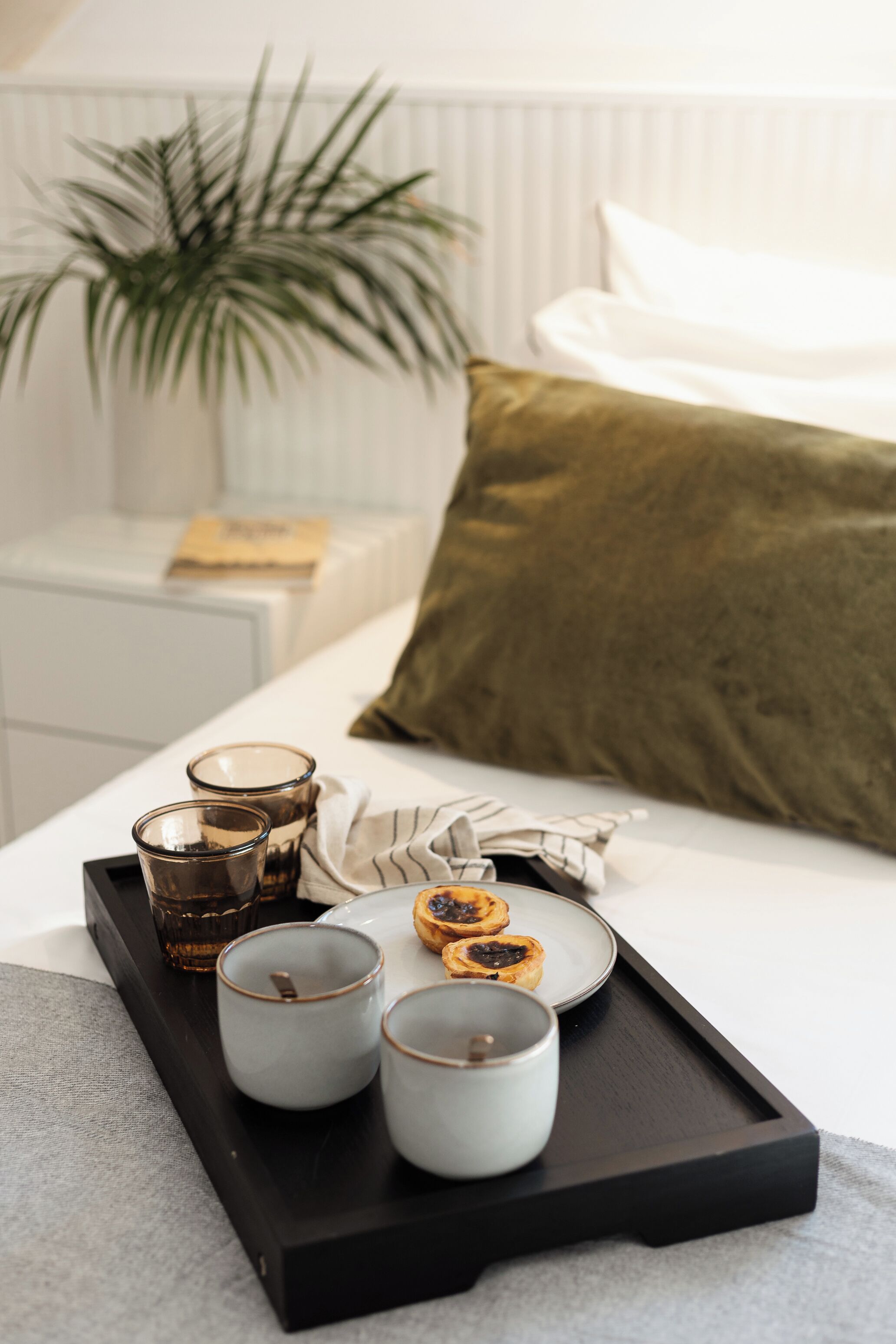 A tray with cups and pastries on a bed.