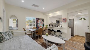 Une chambre moderne comprenant un lit, une table à manger, des chaises, un coin cuisine et une salle de bain.