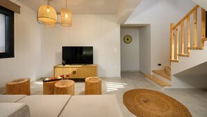 Un salon moderne doté d’un téléviseur à écran plat, de meubles en bois et d’un escalier.