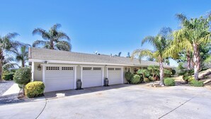 Una casa a un piano con garage, circondata da palme e giardini curati.