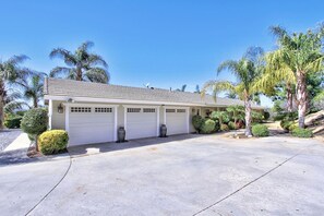 A single-story house with a garage, surrounded by palm trees and well-maintained landscaping. - Delgado way- Charming home on 3 acres w/ Vineyards (Temecula)
