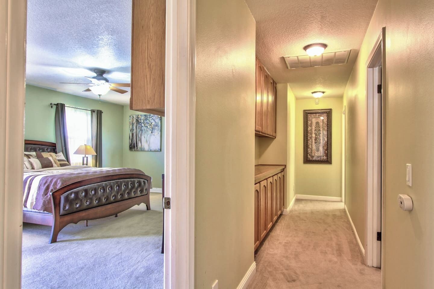 A bedroom with a bed, a ceiling fan, and a window with curtains.