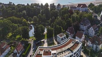A modern building with a curved roof, surrounded by residential houses and a body of water.