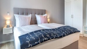A bedroom with a bed, bedside lamps, a wardrobe, and a bedside table. - 4 Star Holiday Home in Travemunde (Lübeck)