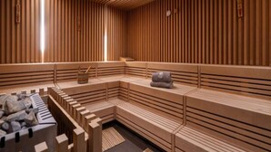 A sauna with wooden slats, benches, and a stone bench area. - 4 Star Holiday Home in Travemunde (Lübeck)