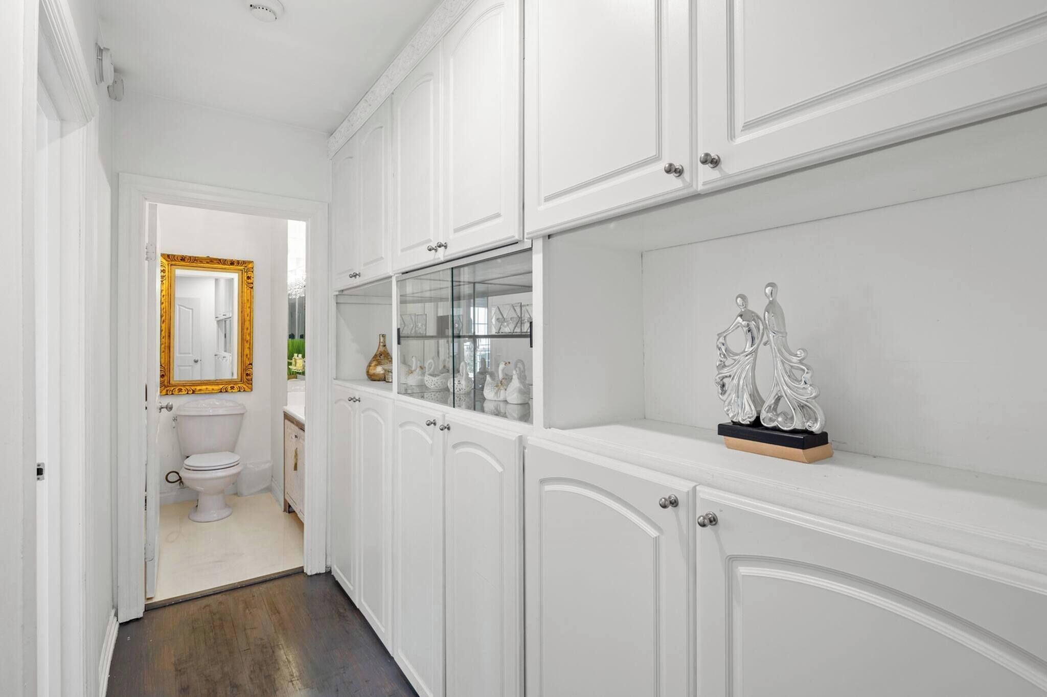 A hallway with white cabinetry, a glass display case, and a decorative silver figure.