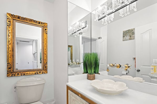 A bathroom with a white toilet, a large mirror with a gold frame, a white sink with a decorative bowl, and a chandelier above the mirror. - Beverly Hills Main House 3BR Hot Tub (Beverly Hills)