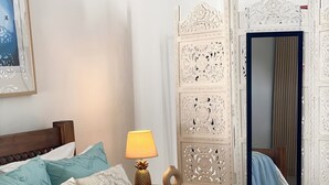 A neatly made bed with patterned pillows, a bedside lamp, and a decorative screen.
