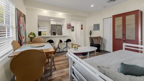 Una habitació amb un llit, taula de menjador amb cadires, zona de cuina i bany.