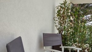 A corner with two white folding chairs with dark cushions, a white wall, and a potted plant with green leaves.