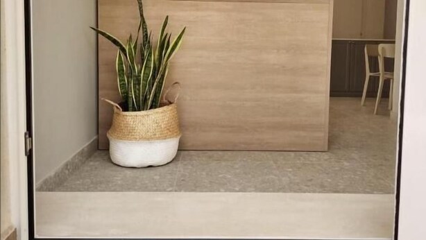 A modern interior with a wooden reception desk, a potted plant, and a 'hello' doormat.