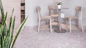 A modern interior with a round table, two chairs, a potted plant, and a textured wall.
