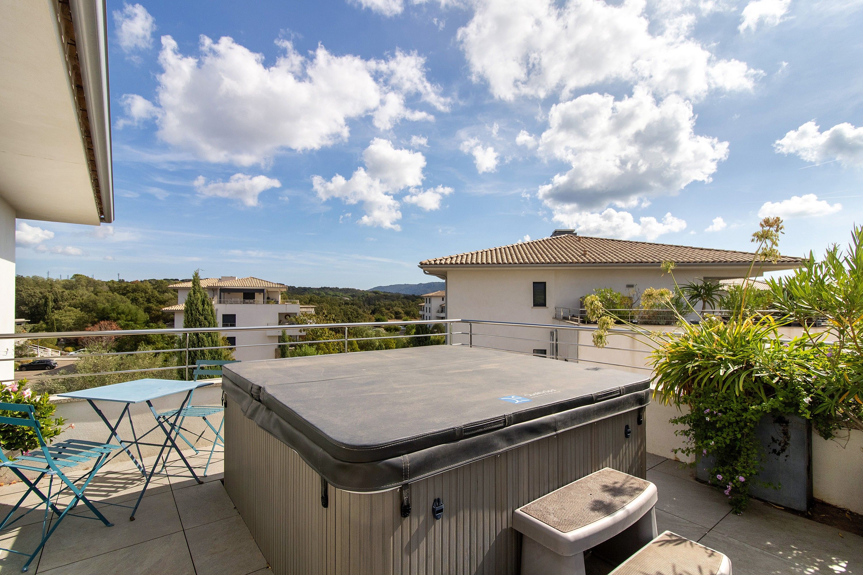 Une terrasse sur le toit dotée d’un jacuzzi, de mobilier d’extérieur et offrant une vue sur les bâtiments et les collines environnants.