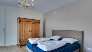 A bedroom with a bed, a wooden wardrobe, and a chandelier. - Achterhoek Villa With Heated Pool (Aalten)