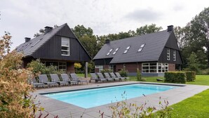 A modern house with a swimming pool, two lounge chairs, and a well-maintained lawn. - Achterhoek Villa With Heated Pool (Aalten)