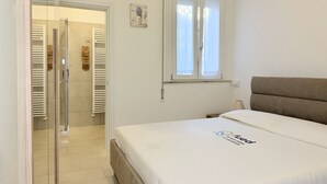 Une chambre à coucher comprenant un lit, une fenêtre, une douche et une porte donnant sur une salle de bain.