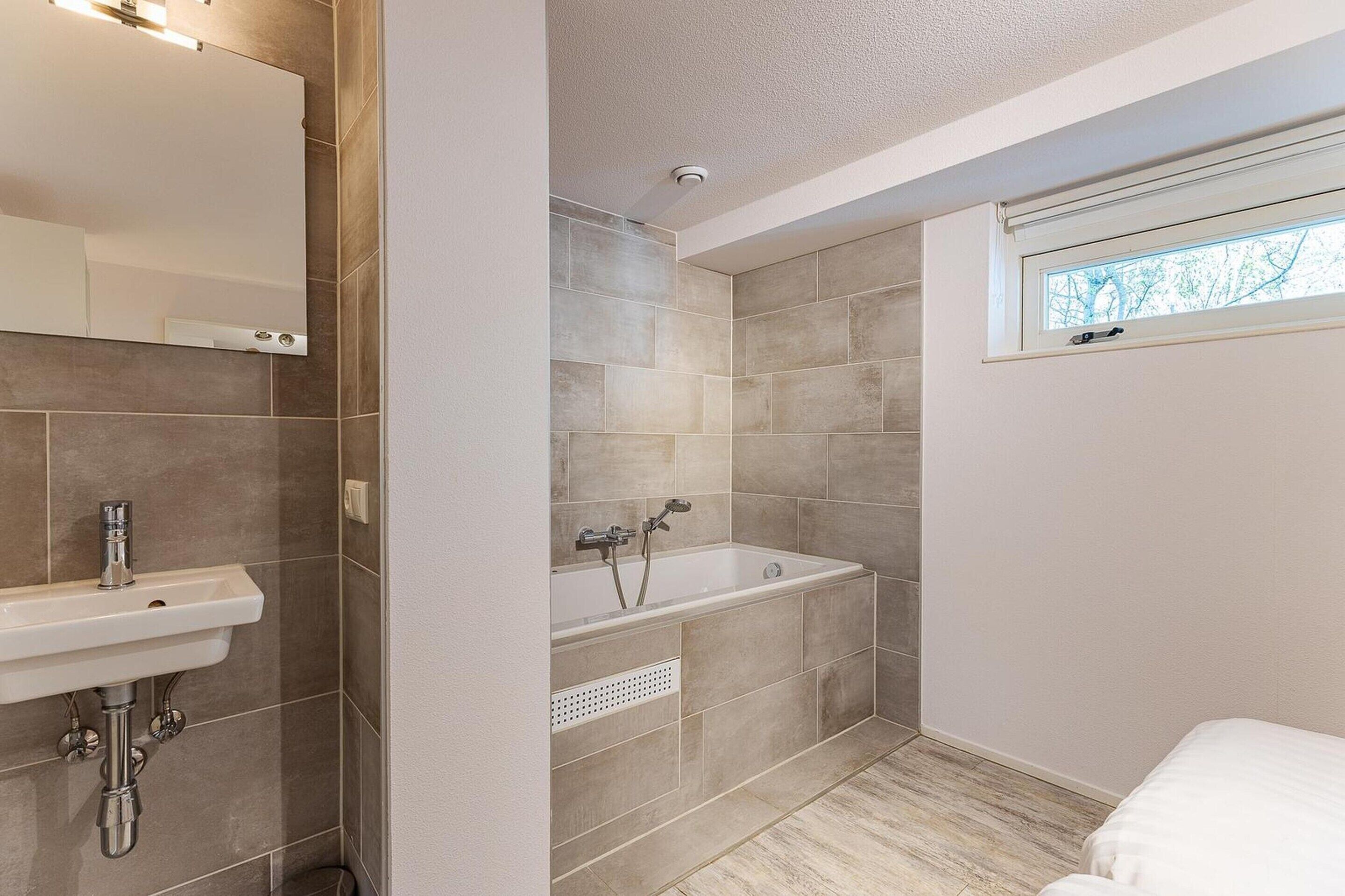 A bathroom with a sink, bathtub, and a window.