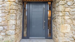 A stone facade with a dark-colored door and a wooden overhang. - Lower Moorwood (Newton Abbot)