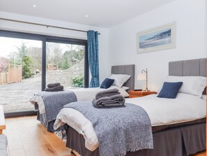 Ein Schlafzimmer mit zwei Betten, einem großen Fenster und Blick ins Freie.