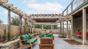 A covered patio area with wooden furniture and a pergola structure. - Lower Moorwood (Newton Abbot)