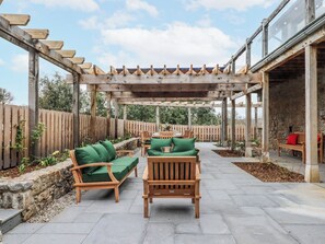 Ein überdachter Patio-Bereich mit Holzmöbeln und einer Pergola.