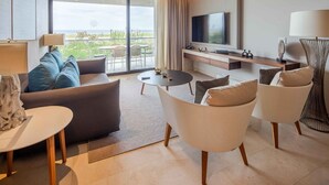 A modern hotel room with a sofa, armchairs, a coffee table, a TV, and a balcony with outdoor seating. - 1-bedroom suite at Solaz, A Luxury Collection Resort, Los Cabos (San José del Cabo)