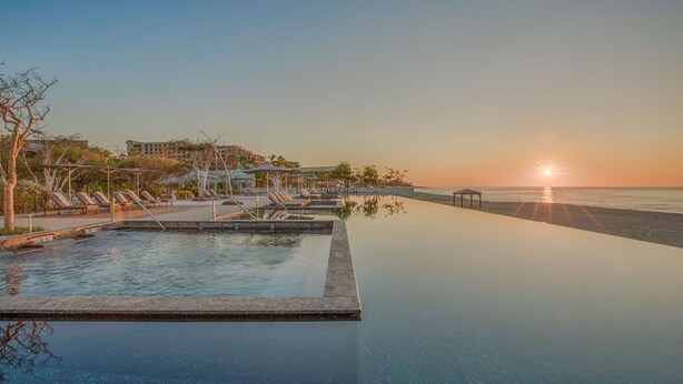 An infinity pool with lounge chairs, a beach, and a sunset. - 1-bedroom suite at Solaz, A Luxury Collection Resort, Los Cabos (San José del Cabo)
