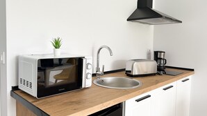 A compact kitchen with a microwave, toaster, sink, and a coffee maker. - Apartamentos El Camino Resorts (Cóbreces)