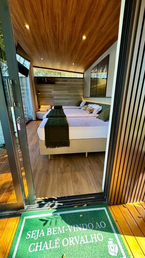 A modern bedroom with a large bed, a wooden ceiling, and a view through a glass door. - Sitio Castelinho Hotel Fazenda (Cesário Lange)