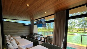 A modern hotel room with two beds, a TV, and a balcony overlooking a body of water.