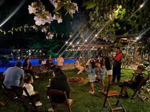 An outdoor seating area with chairs and tables, surrounded by greenery and string lights. - Sitio Castelinho Hotel Fazenda (Cesário Lange)