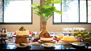 A buffet table with various desserts and a central decorative vase.