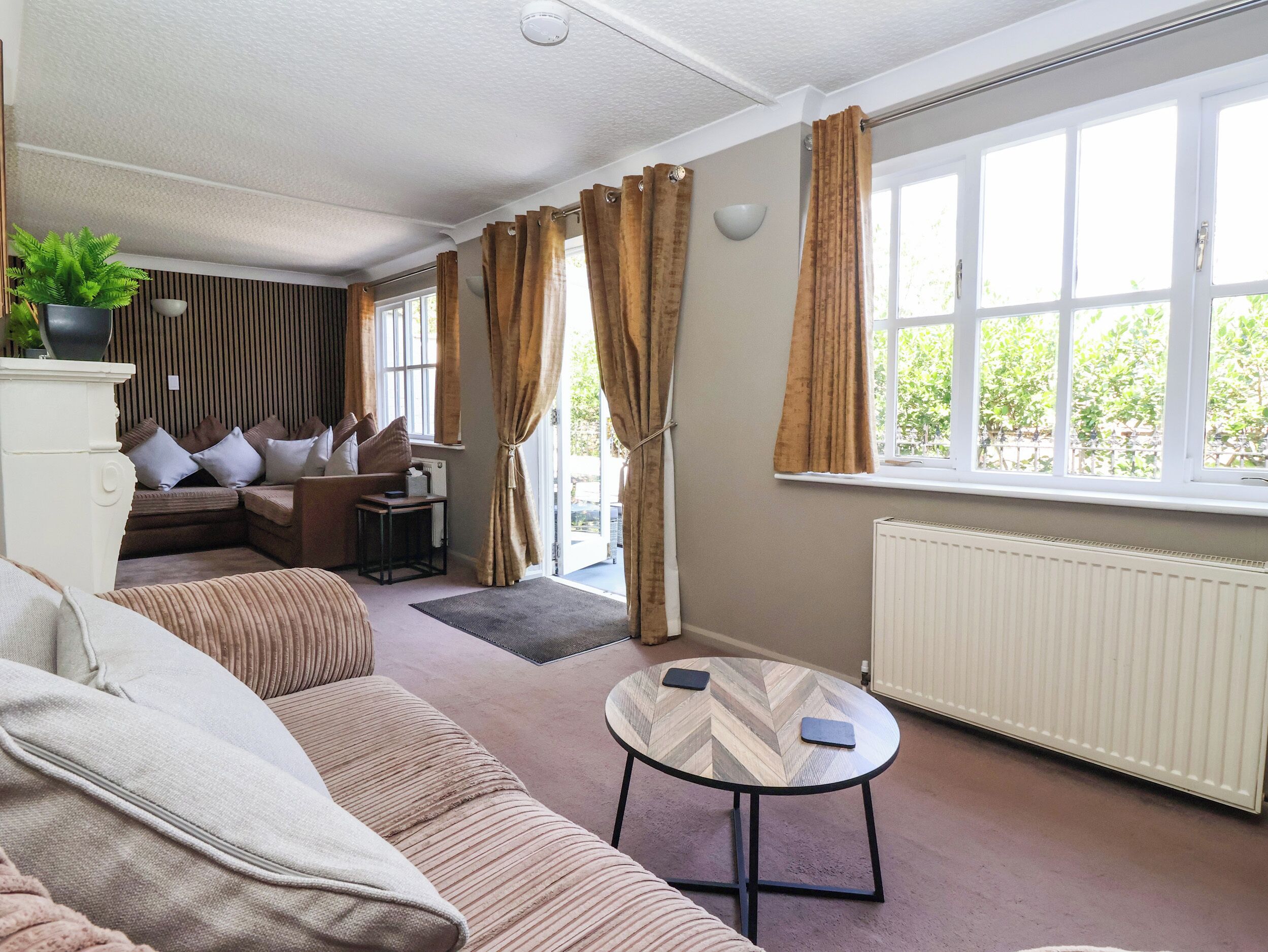 A living room with a sofa, a small table, a radiator, and a window with curtains.