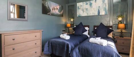 A hotel room with two beds, a dresser, and artwork on the walls.