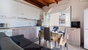 Una cocina moderna con armarios blancos, una mesa de comedor y un sofá.