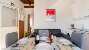 Un comedor con una mesa para cuatro, un sofá, una lavadora y un microondas.